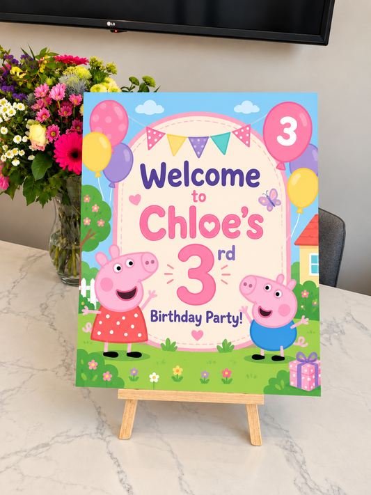 Personalised pig birthday welcome sign with two cartoon pigs on a tabletop easel